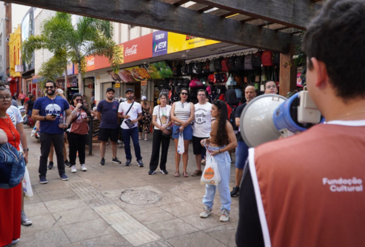 Grupo de pessoas participa de atividade cultural ao ar livre no centro da cidade.