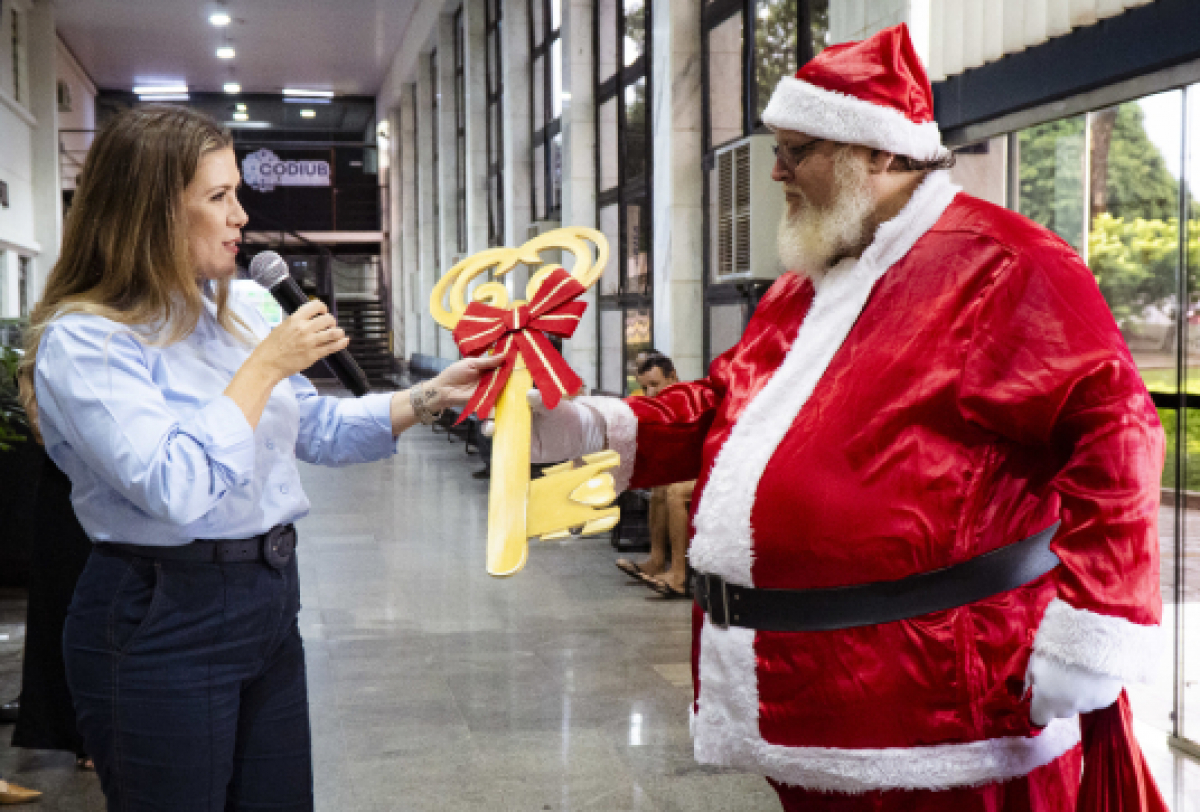 A prefeita entrega uma chave simbólica ao Papai Noel em um evento público.