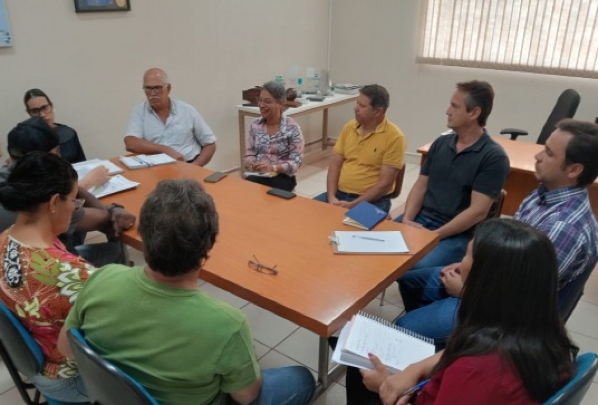 Reunião de trabalho com um grupo de pessoas discutindo em torno de uma mesa em um ambiente de escritório.