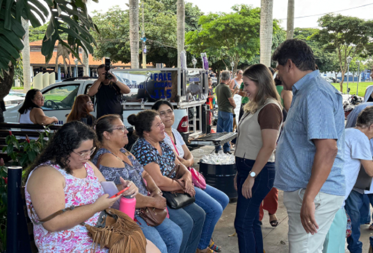 Encontro comunitário ao ar livre com interação entre moradores e representantes.