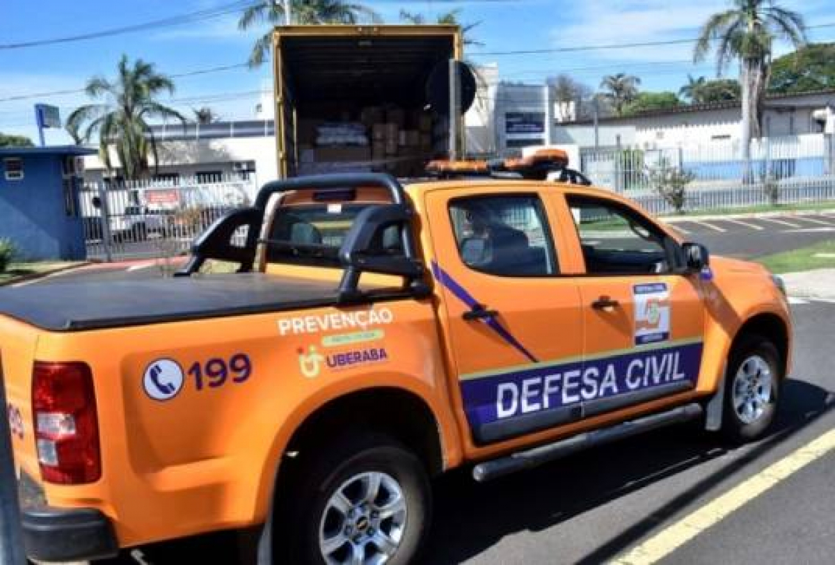 Veículo da Defesa Civil próximo a um caminhão em operação de distribuição.