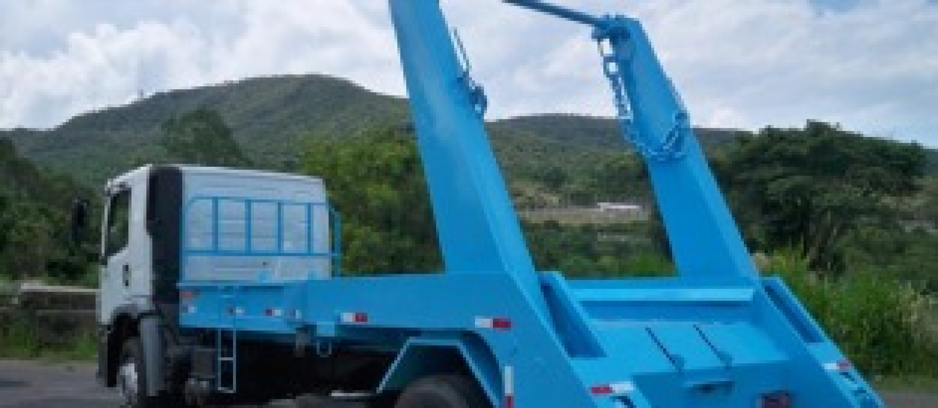 Caminhão equipado com sistema de caçamba basculante para transporte e descarte de resíduos e materiais.