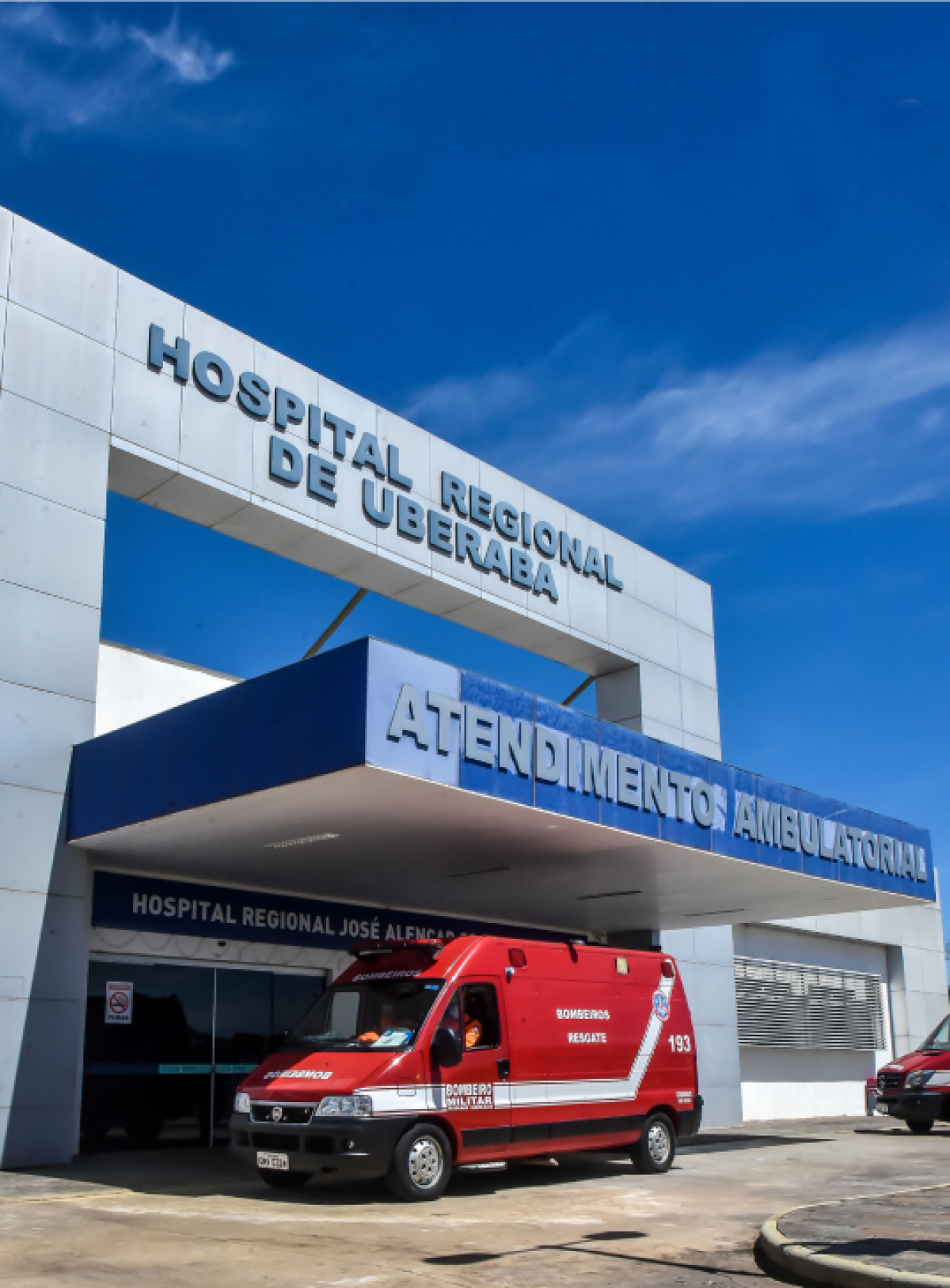 Imagem da fachada do Hospital Regional de Uberaba, com uma ambulância dos Bombeiros de Minas Gerais estacionada na área de Atendimento Ambulatorial.
