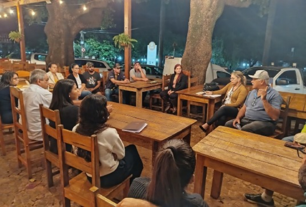 Reunião informal em ambiente externo com várias pessoas discutindo em círculo.