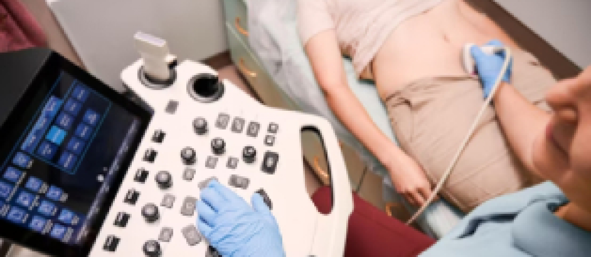 A imagem mostra uma profissional de saúde realizando um exame de ultrassonografia abdominal em uma paciente.