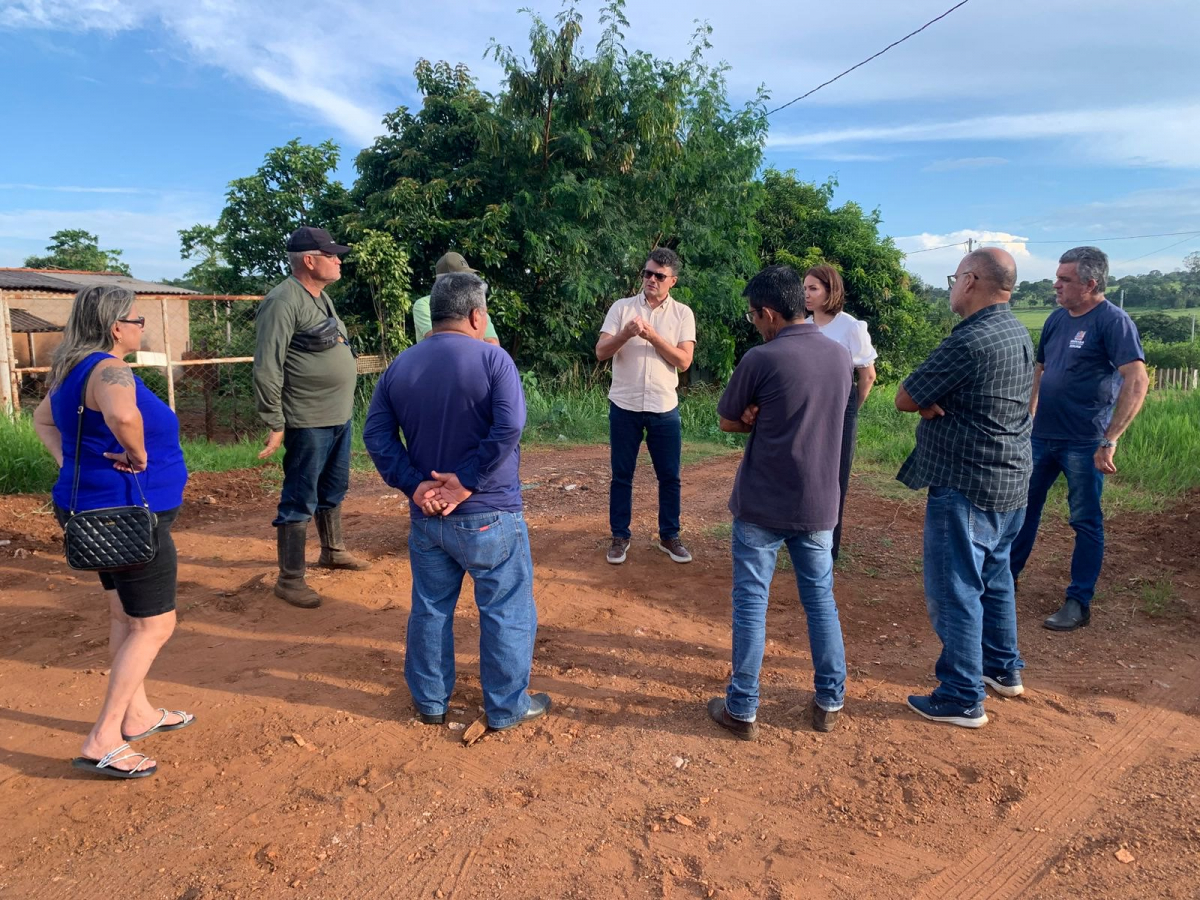 Grupo de pessoas discute melhorias em estrada de terra em ambiente rural.