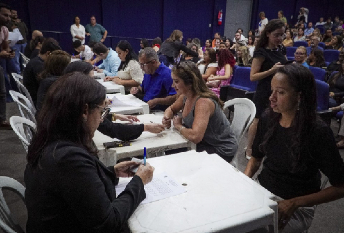 Público participa de atendimento presencial em evento com várias mesas de cadastro ou orientação.