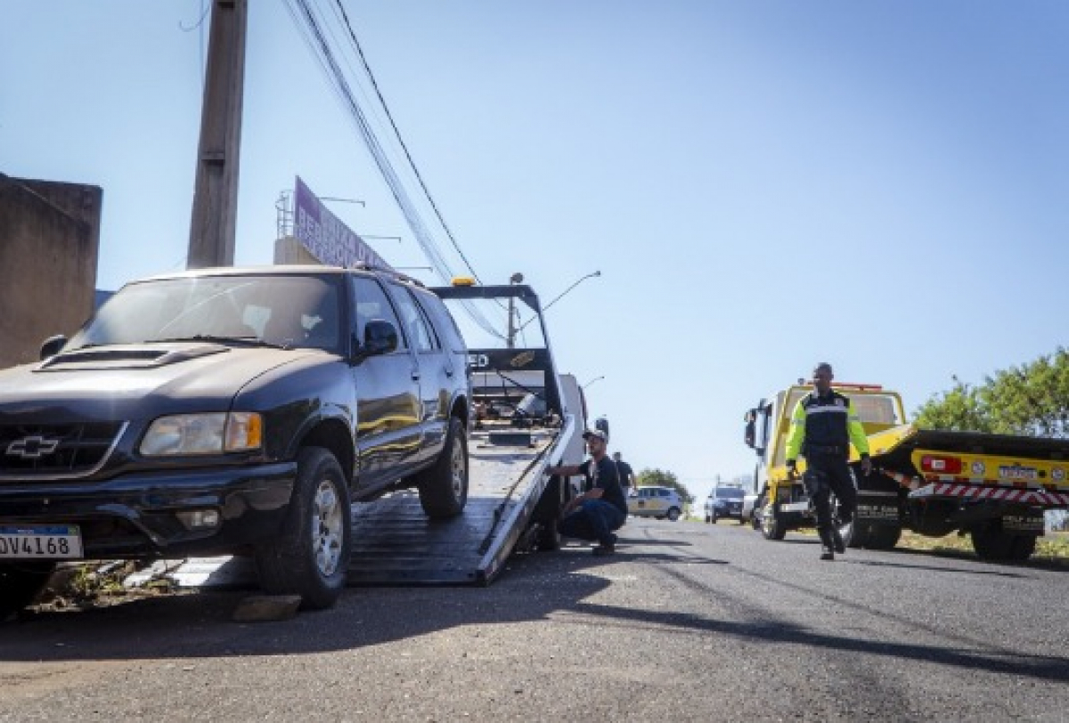 Caminhonete é rebocada por guincho com apoio de agentes de trânsito em via pública.