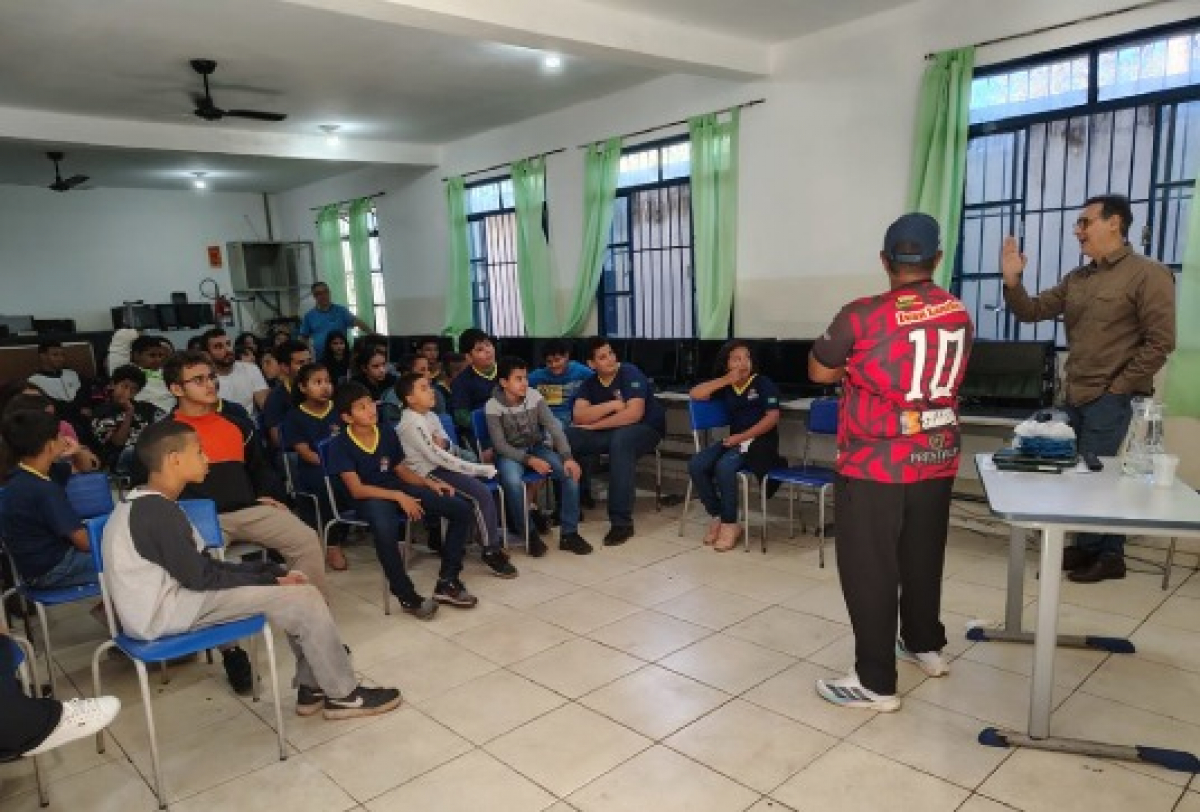 Palestra educativa é realizada para jovens em sala de aula, promovendo diálogo e aprendizado. 