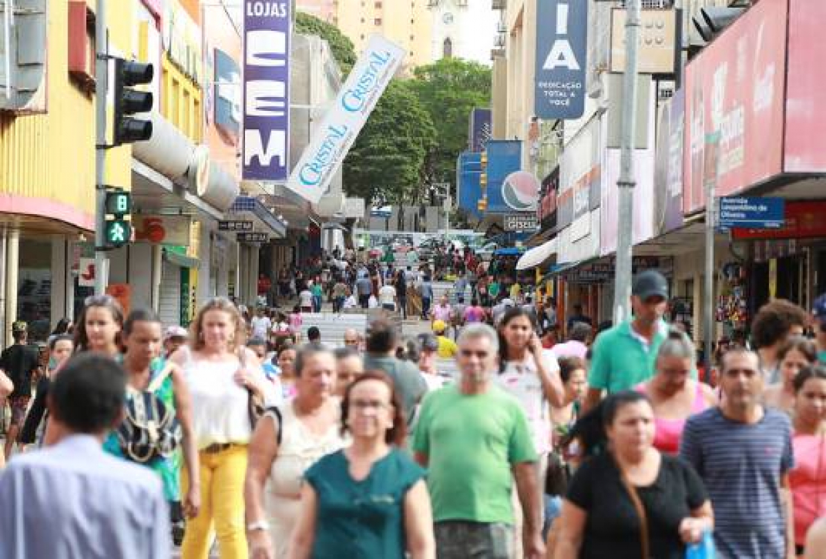 Rua comercial movimentada com pedestres e diversas lojas ao longo do calçadão.