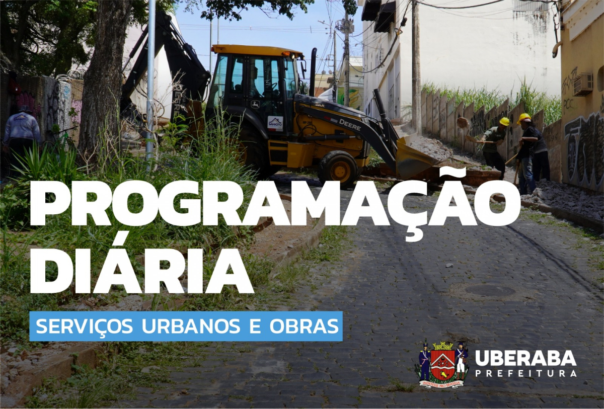 A imagem mostra uma cena de construção em uma rua de paralelepípedos com uma retroescavadeira e trabalhadores usando capacetes amarelos.