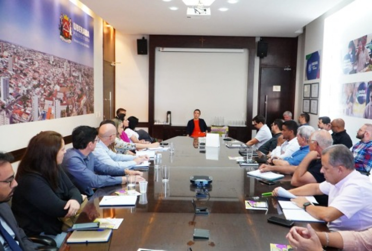 Reunião formal com diversos participantes acontece em uma sala da prefeitura .