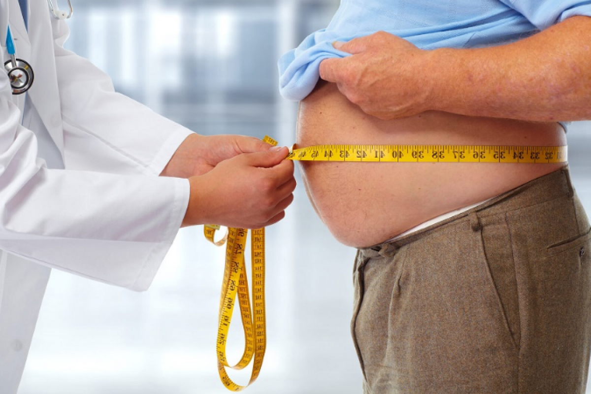 Profissional de saúde mede a circunferência abdominal de um paciente para avaliar a obesidade e os riscos associados à saúde.