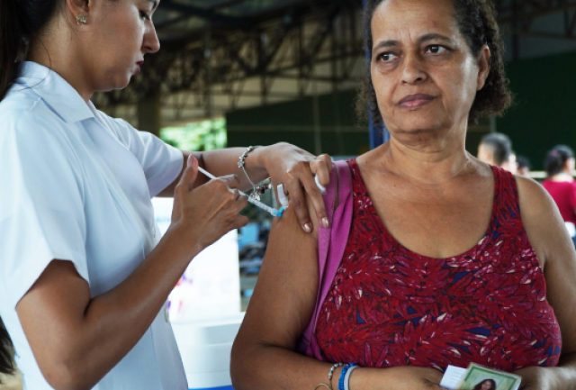 Mulher recebe vacina em campanha de imunização em ambiente comunitário.