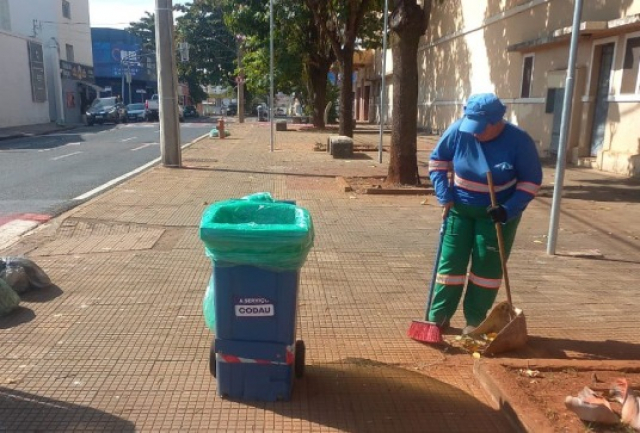 Funcionário da limpeza urbana varre calçada em área central com carrinho identificado pelo Codau.