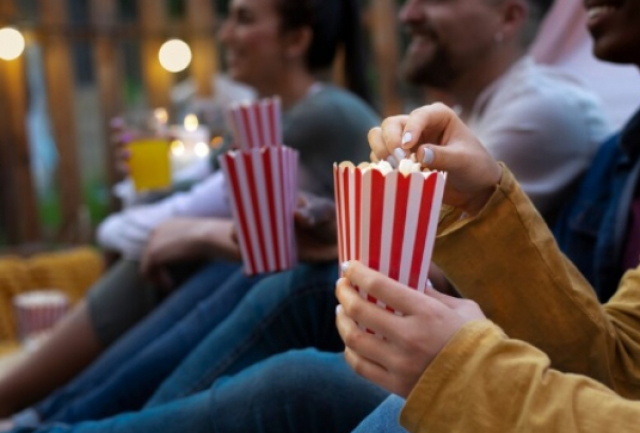Sessão de cinema ao ar livre reúne pessoas em clima descontraído com pipoca e diversão.