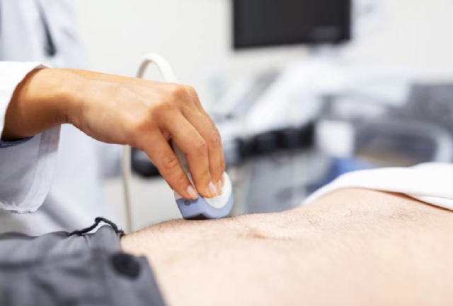 Profissional realiza exame de ultrassom abdominal em paciente utilizando um transdutor.