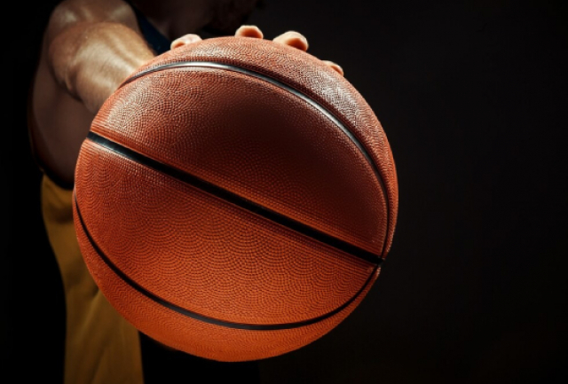 A imagem mostra um close-up de uma pessoa segurando uma bola de basquete.