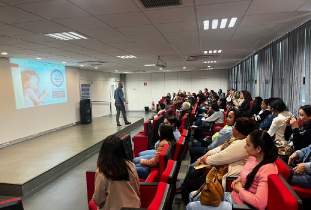 Profissionais acompanham palestra educativa sobre cuidados com a primeira infância em auditório.